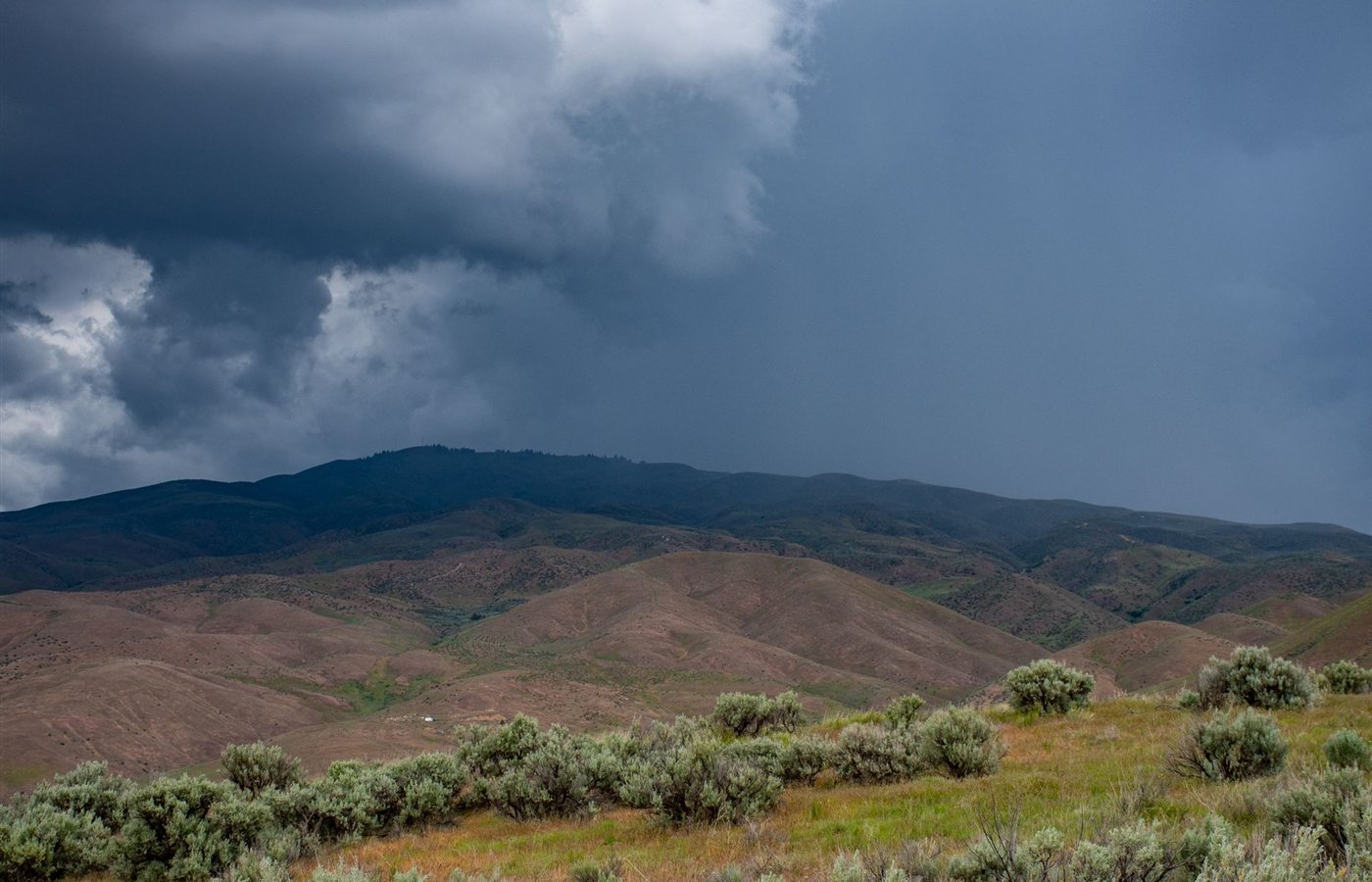 A picturesque view of storm clouds looming over a peaceful mountain landscape, capturing nature's raw beauty.