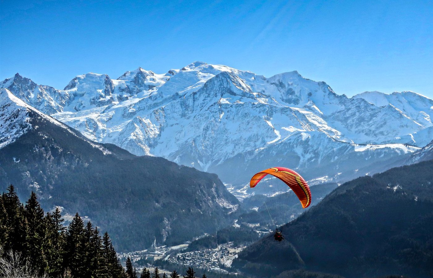 A thrilling paraglider soars over Mont Blanc in Passy, capturing the stunning winter mountain scenery.