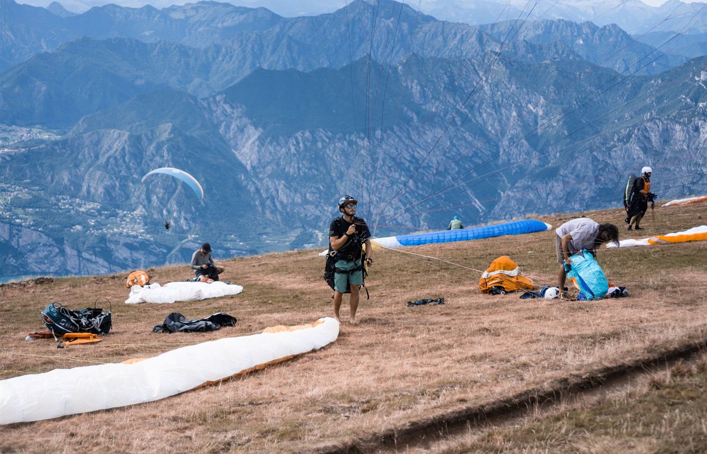Paragliders set up equipment on a scenic plateau, ready to take off into the mountainous landscape.