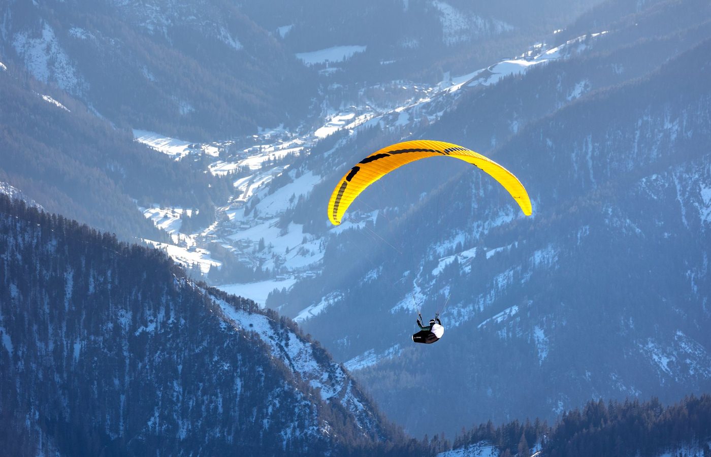 Experience the thrill of paragliding over the scenic, snow-covered Dolomites in Trentino-South Tyrol, Italy.